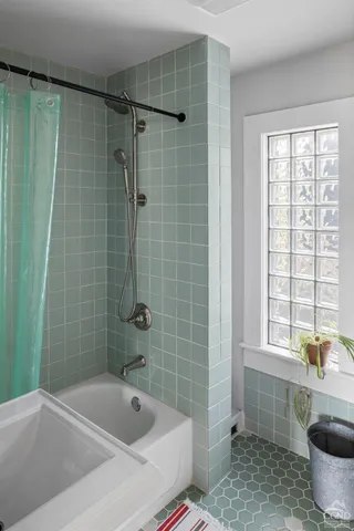 a bathroom with a tub a window and a shower