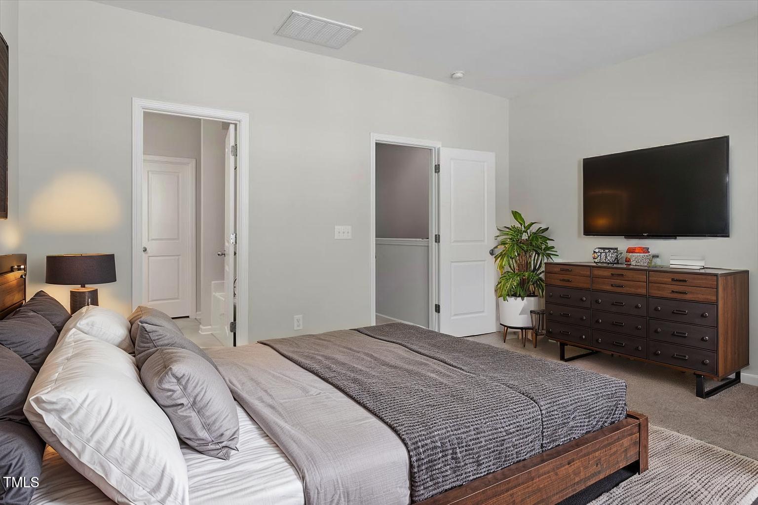 709 Wickham Ridge Road Apex, NC 27539 - Photo 7 of 36 a bedroom with a bed and a flat screen tv