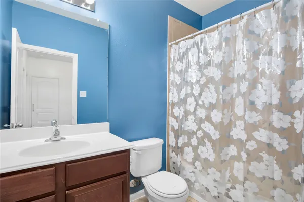 a bathroom with a sink a toilet a mirror and shower curtain