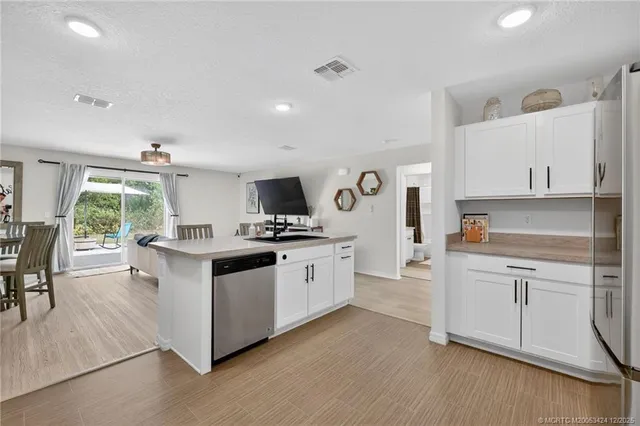 a kitchen with stainless steel appliances white cabinets and wooden floors