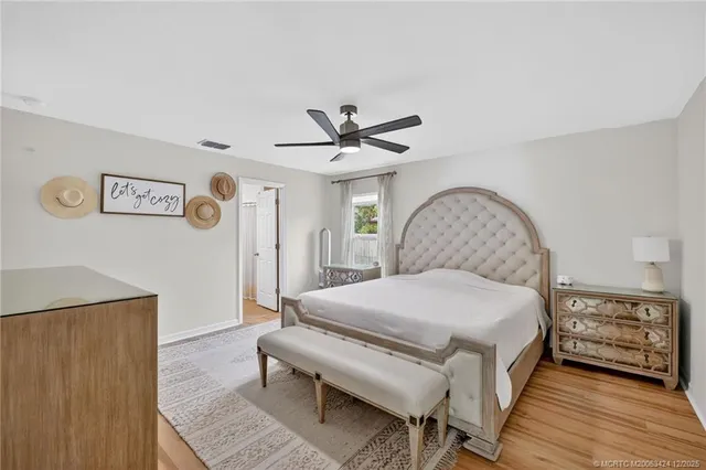 a bedroom with a bed and a ceiling fan with wooden floor