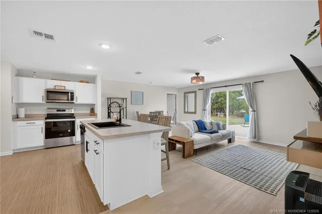 a living room with stainless steel appliances furniture and a kitchen view