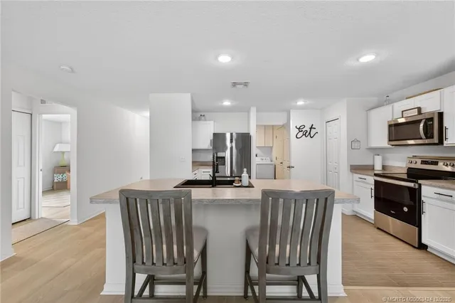 a kitchen with stainless steel appliances granite countertop a stove a sink a microwave a dining table and chairs