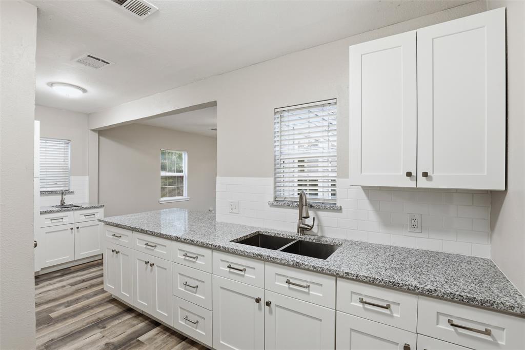 227 South Hampton Road Dallas, TX 75208 - Photo 15 of 32 Kitchen with light stone counters, white cabinets, backsplash, and light wood-style floors