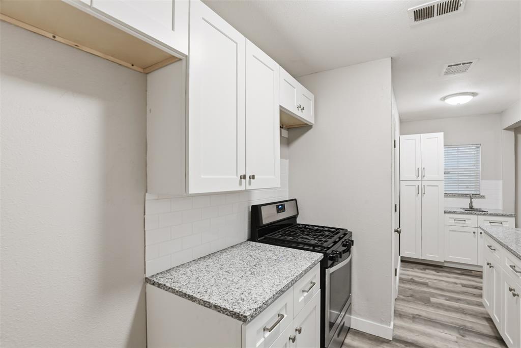 227 South Hampton Road Dallas, TX 75208 - Photo 16 of 32 Kitchen featuring gas range, white cabinetry, light stone countertops, and backsplash