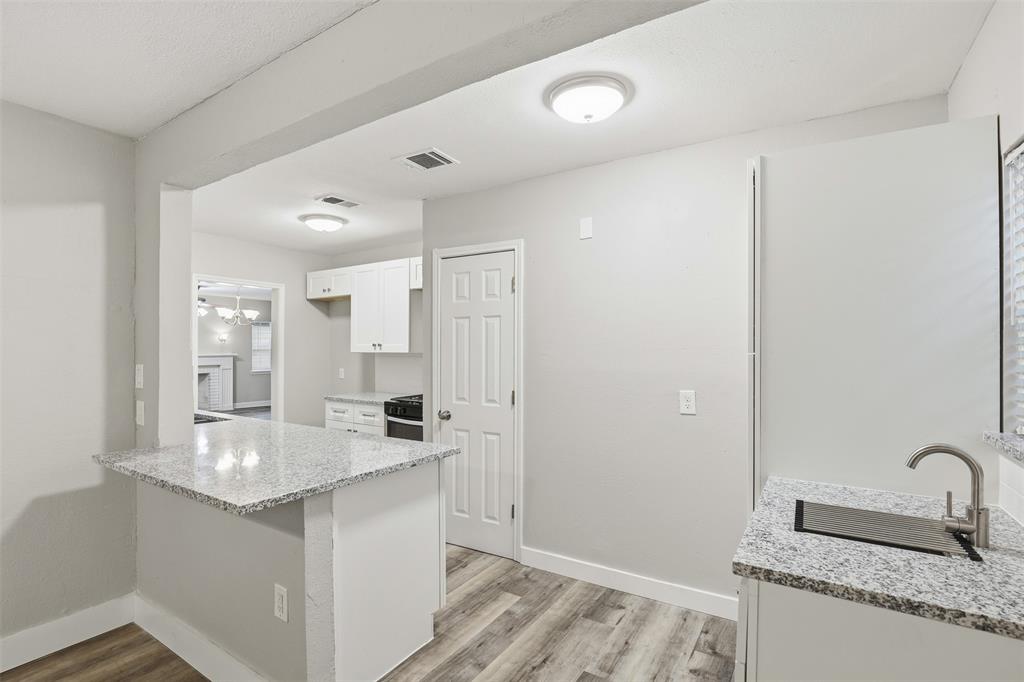 227 South Hampton Road Dallas, TX 75208 - Photo 17 of 32 Kitchen featuring light stone counters, white cabinets, a peninsula, light wood-type flooring, and gas range