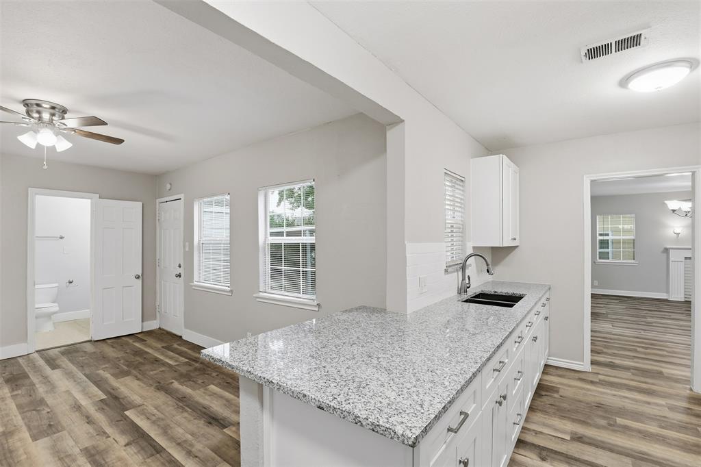 227 South Hampton Road Dallas, TX 75208 - Photo 18 of 32 Kitchen with light stone countertops, light wood-style floors, white cabinets, and ceiling fan