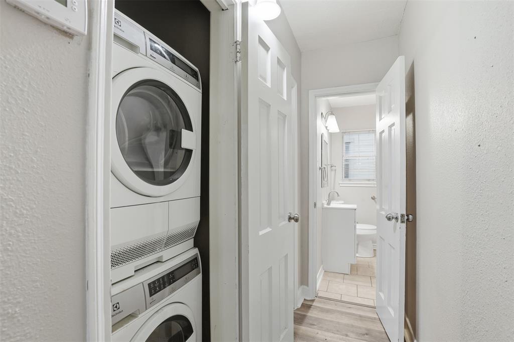 227 South Hampton Road Dallas, TX 75208 - Photo 29 of 32 Laundry room featuring a textured wall, stacked washer / drying machine, and light wood-style floors