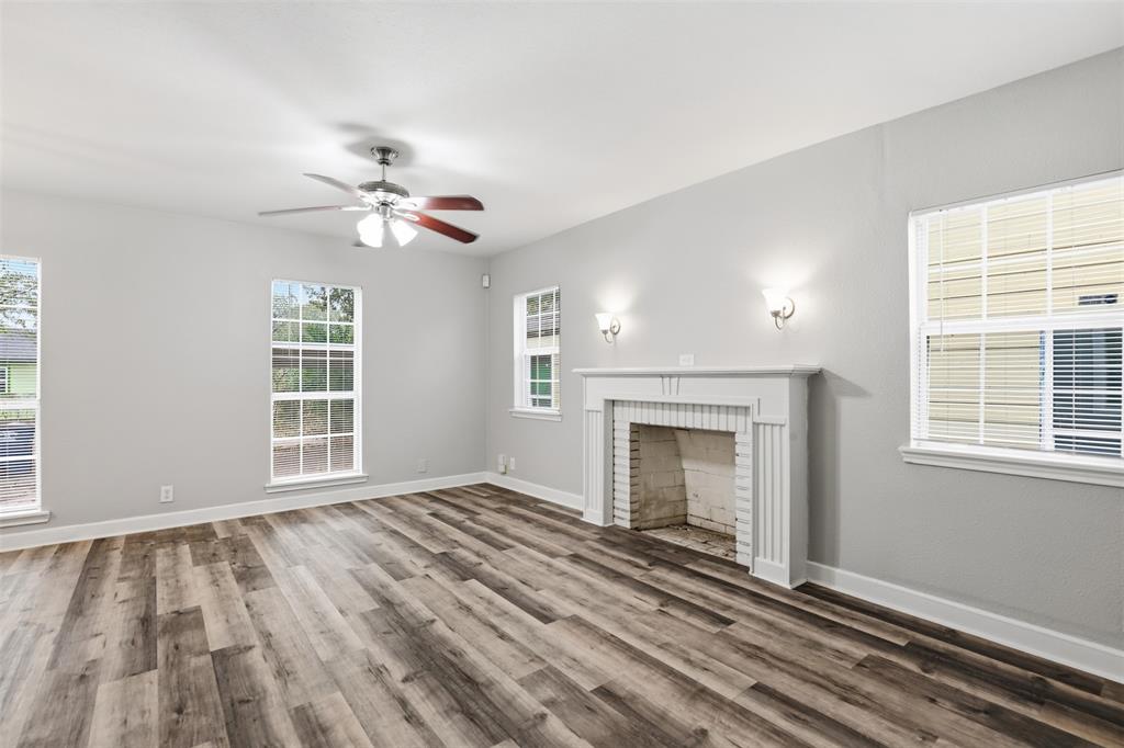 227 South Hampton Road Dallas, TX 75208 - Photo 8 of 32 Unfurnished living room with healthy amount of natural light, wood finished floors, a fireplace, and ceiling fan