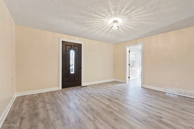 a view of an empty room with wooden floor and a ceiling fan