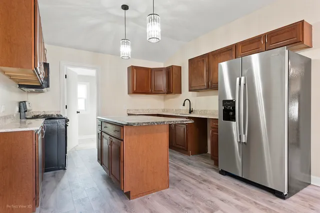 a kitchen with stainless steel appliances granite countertop a refrigerator a stove a sink and a refrigerator with wooden floor