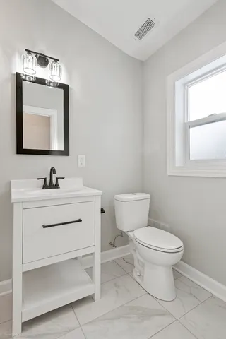 a bathroom with a toilet sink vanity and mirror