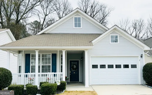 a view of a white house with large windows and a small yard