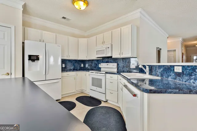 a kitchen with stainless steel appliances granite countertop a sink a stove and white cabinets