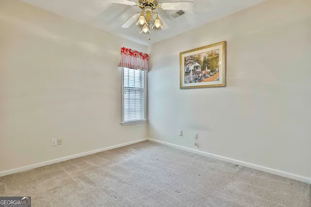 an empty room with a window and a chandelier fan