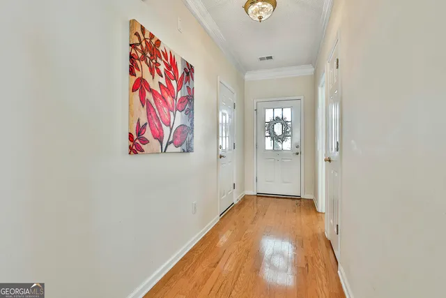 a view of a hallway with wooden floor and a bathroom