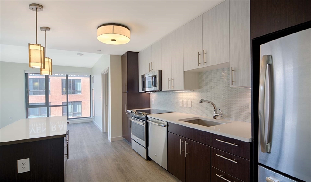 1 Canal Street, Unit 738 Boston, MA 02114 - Photo 2 of 12 a kitchen with stainless steel appliances granite countertop a sink a stove and a refrigerator