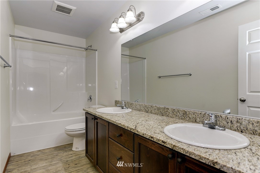 19520 Grand Mound Way Southwest Rochester, WA 98579 - Photo 26 of 34 a bathroom with a granite countertop sink a toilet a mirror and shower