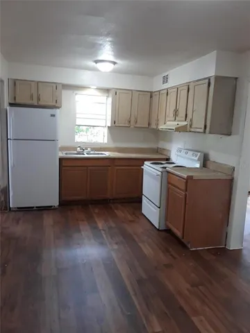 a kitchen with stainless steel appliances granite countertop a sink a stove a refrigerator with grey cabinets and wooden floor