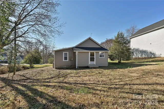 a view of a yard in front of a house with large trees
