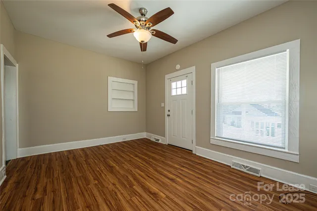 a view of an empty room with wooden floor and a window