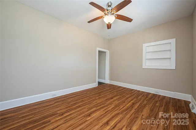 an empty room with wooden floor and a ceiling fan