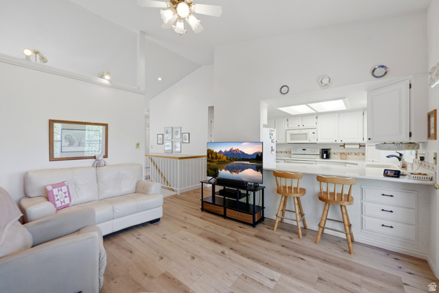 3766 Cardiff Circle Bountiful, UT 84010 - Photo 14 of 46 Open-concept living area featuring vaulted ceilings, wood-finish flooring, and a kitchen pass-through with a breakfast bar
