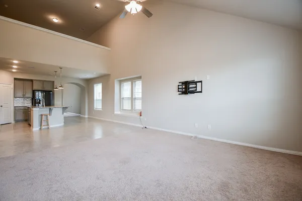 an empty room with chandelier fan and windows