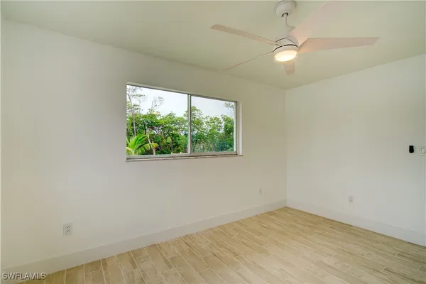 an empty room with wooden floor fan and window