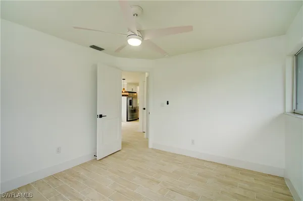 an empty room with a fan & a window