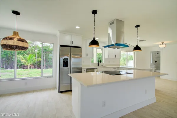 a kitchen with stainless steel appliances granite countertop a sink a kitchen island a stove and a wooden floors