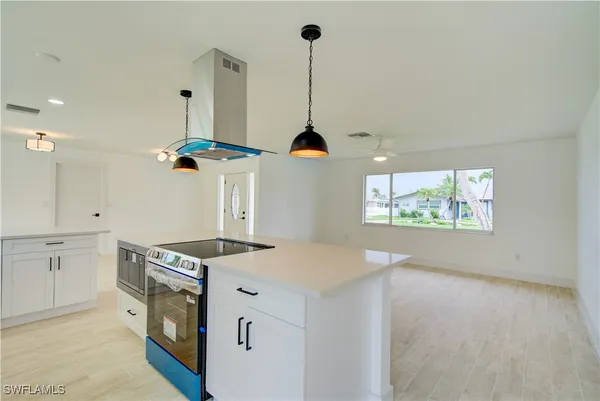 a kitchen with a stove a sink a chimney and a window