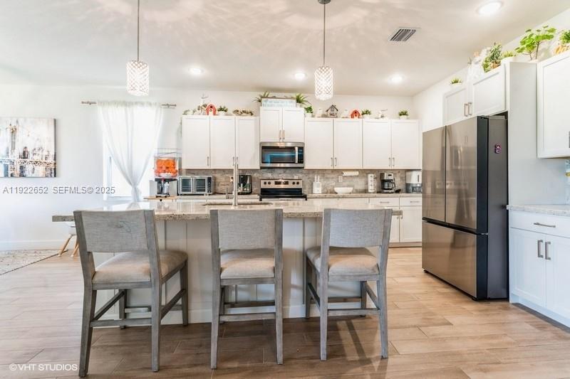 16033 Southwest 277th Street Homestead, FL 33031 - Photo 12 of 37 a kitchen with stainless steel appliances kitchen island granite countertop a table chairs and a refrigerator