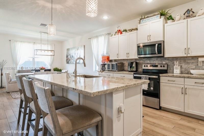 16033 Southwest 277th Street Homestead, FL 33031 - Photo 17 of 37 a kitchen with stainless steel appliances granite countertop a white cabinets and stove top oven