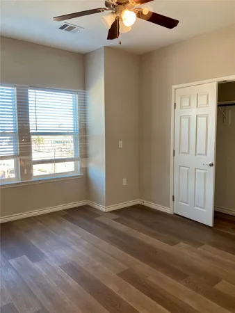 an empty room with wooden floor cabinet and windows