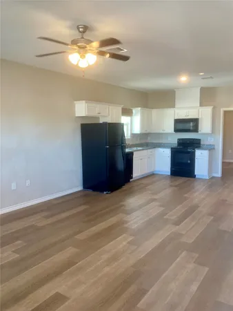 a large kitchen with stainless steel appliances granite countertop a sink dishwasher a stove and a refrigerator with wooden floor