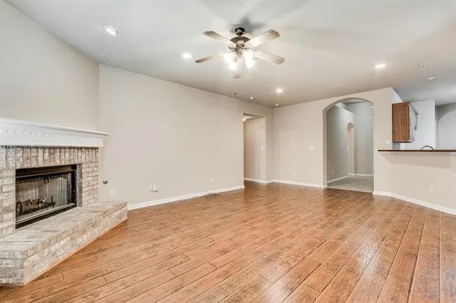 a view of an empty room with wooden floor and a fireplace