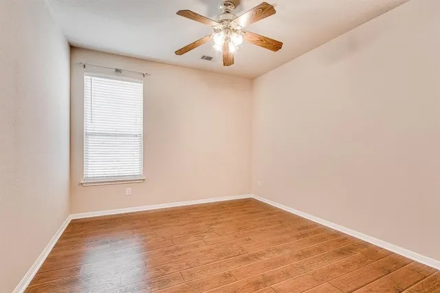 a view of a room with wooden floor and a chandelier fan