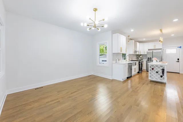 a living room with stainless steel appliances kitchen island granite countertop furniture and a chandelier