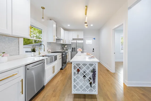 a kitchen with stainless steel appliances granite countertop a sink a stove a refrigerator cabinets and a wooden floor