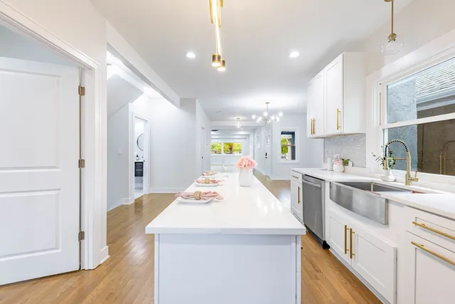 a kitchen with a sink a stove a refrigerator and white cabinets