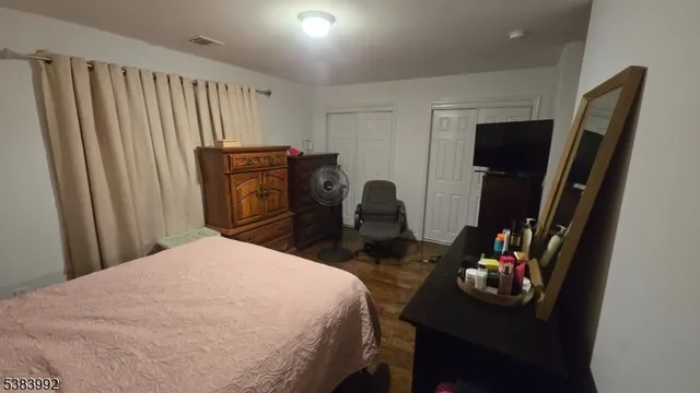 a bedroom with a bed dresser and a flat tv screen
