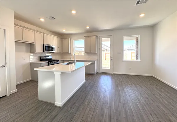 a kitchen with stainless steel appliances granite countertop wooden floors a stove a microwave a sink and a window