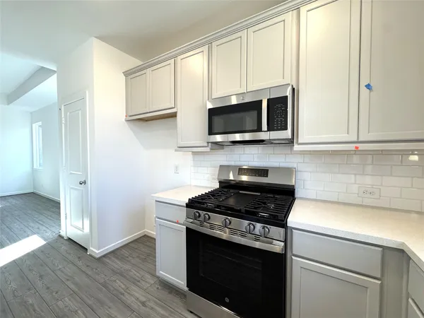 a kitchen with cabinets stainless steel appliances and wooden floor
