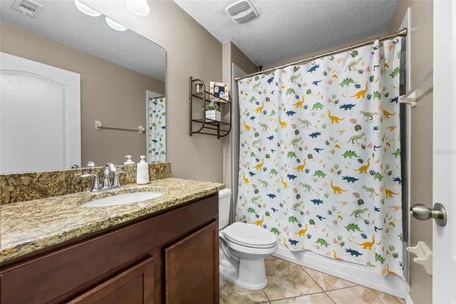 a bathroom with a granite countertop sink a toilet and a shower curtain