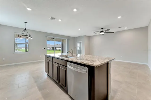a kitchen with granite countertop cabinets a sink dishwasher and a refrigerator