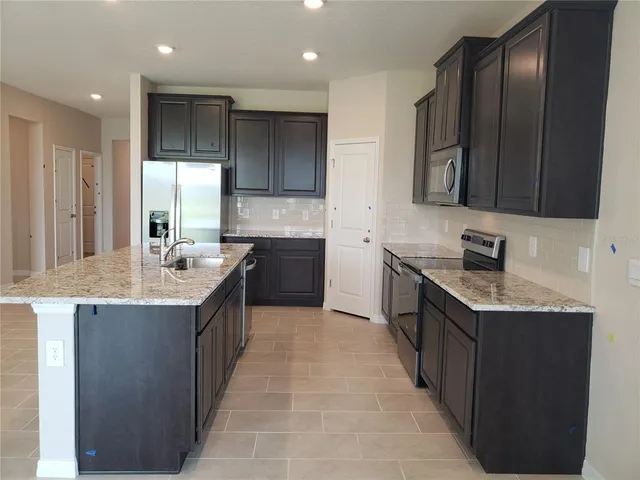 a kitchen with stainless steel appliances granite countertop a sink stove and refrigerator