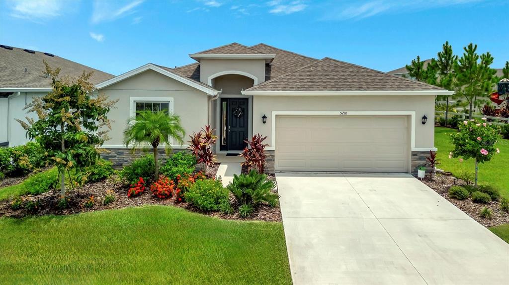 5210 Grove Mill Loop Lakewood Ranch, FL 34211 - Photo 2 of 48 a front view of a house with a garden and plants