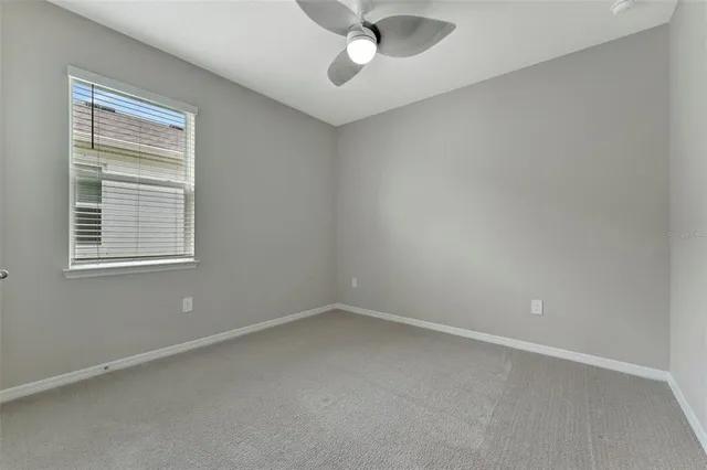 an empty room with a window and a ceiling fan