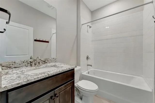 a bathroom with a granite countertop sink a toilet and shower